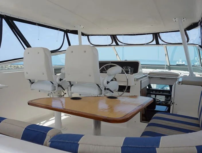Pacific 72 sheltered flybridge with striped seating around a wood table