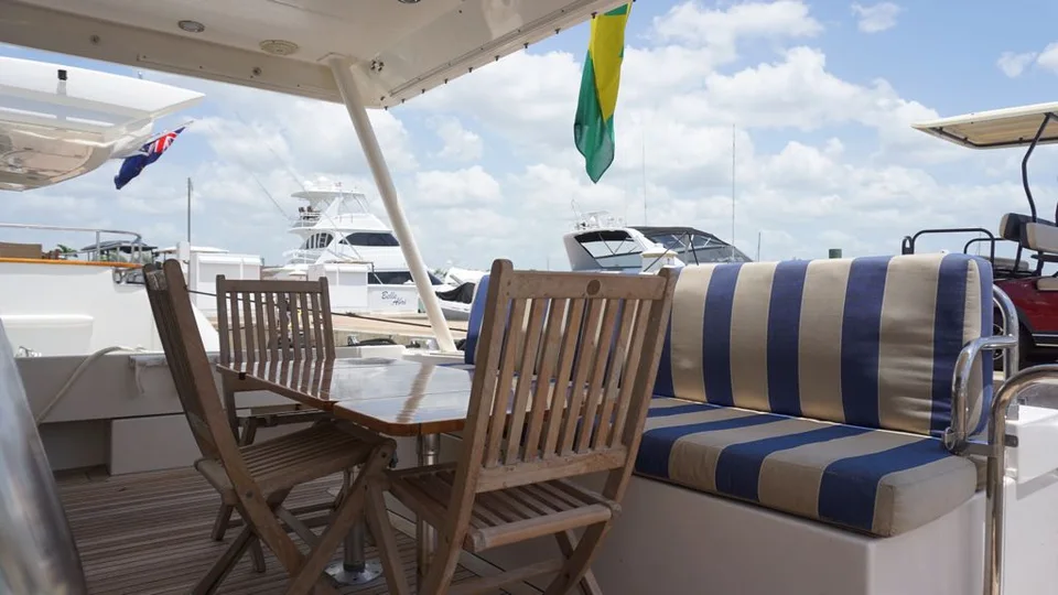 Pacific 72 covered aft dining area with wood chairs and striped bench