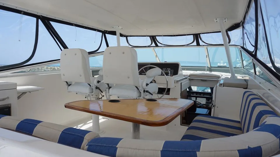 Pacific 72 sheltered flybridge with striped seating around a wood table